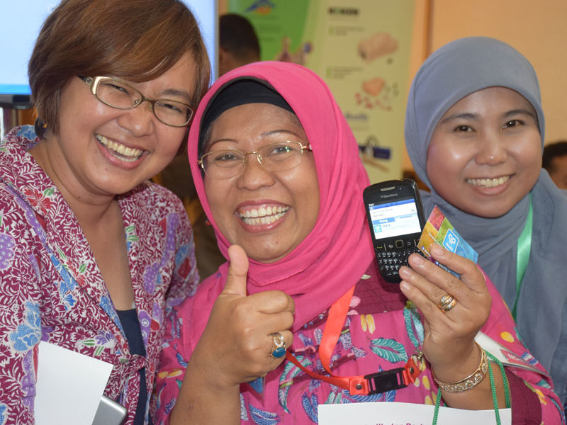 Women in Indonesia smile with the MyChoice family planning mobile app, SKATA.