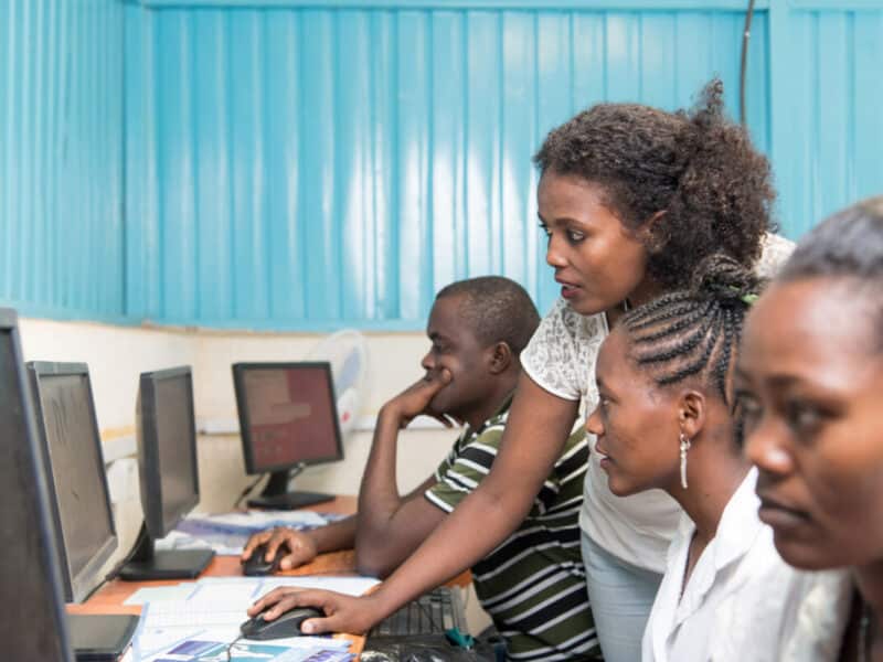 Ethiopian woman helping another woman learn computer skills